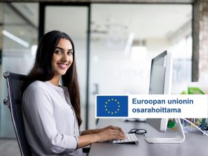 Työllisyysnäkymiä vuodelle 2025 (kuvassa nainen istuu tietokoneen ääressä ja hymyilee)