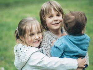 Länsi-Uudenmaan hyvinvointialue luopuu Omaperhe-sivuston maksullisesta versiosta – Lapsiperheiden ja nuorten palvelut Hyvinvointipalvelut-sivustolle (kuvituskuvassa kolme lasta halaa)