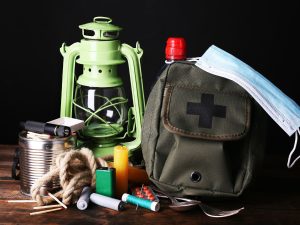 Kuvassa varautumistarvikkeita, kuten reppu, myrskylyhty, lääkkeitä ja tulitikut