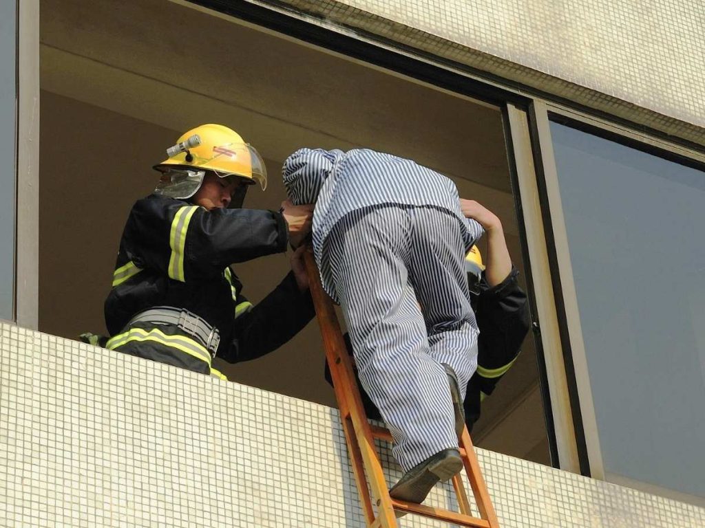 Ihminen poistuu parvekkeelta tikkailla palomiesten avustamina.