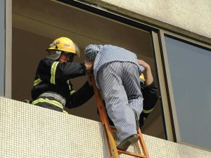 Ihminen poistuu parvekkeelta tikkailla palomiesten avustamina.