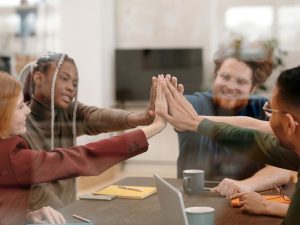 Maakunnallinen järjestökysely Uudellamaalla toimiville yhdistyksille (kuvassa neljä ihmistä istuu pöydän ääressä ja lyö kämmenet toistensa kanssa yhteen)
