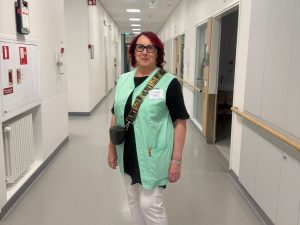 Saattohoidon vapaaehtoinen Kaarina sairaalassa, yllään vihreä vapaaehtoisen liivi.